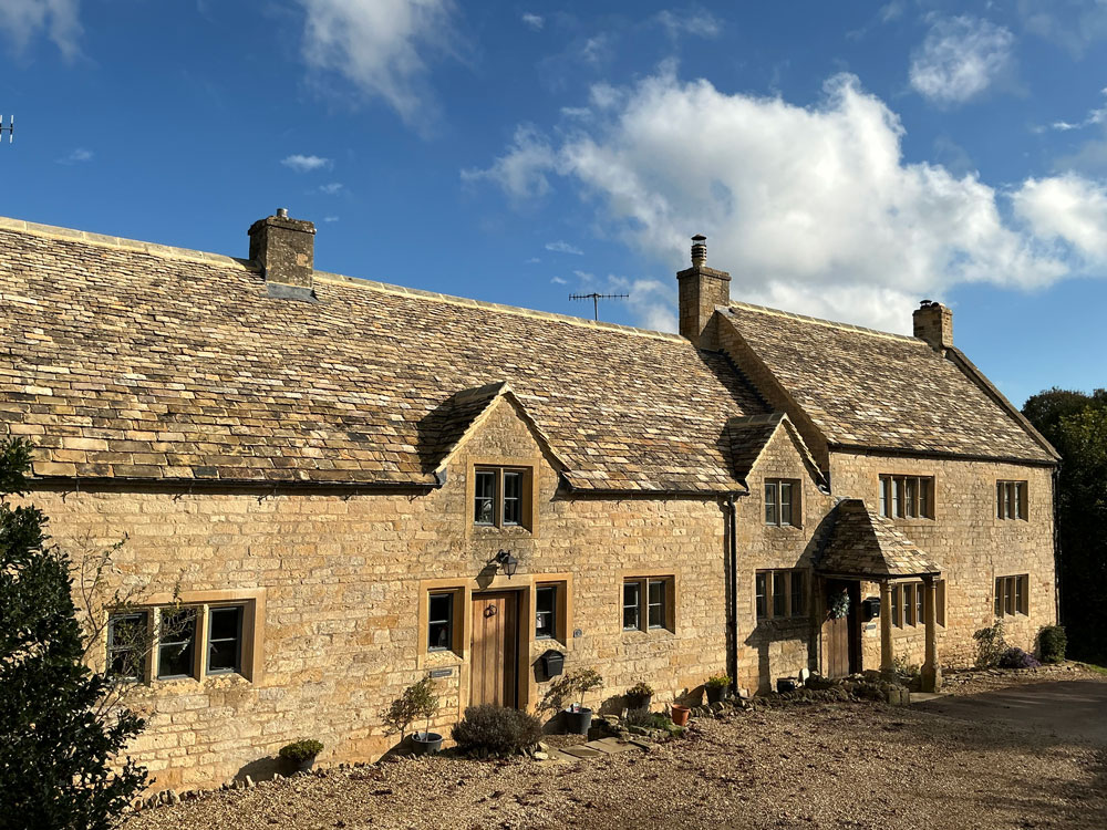 Farmhouse with gabled dormers after Cotswold stone slate re-roof