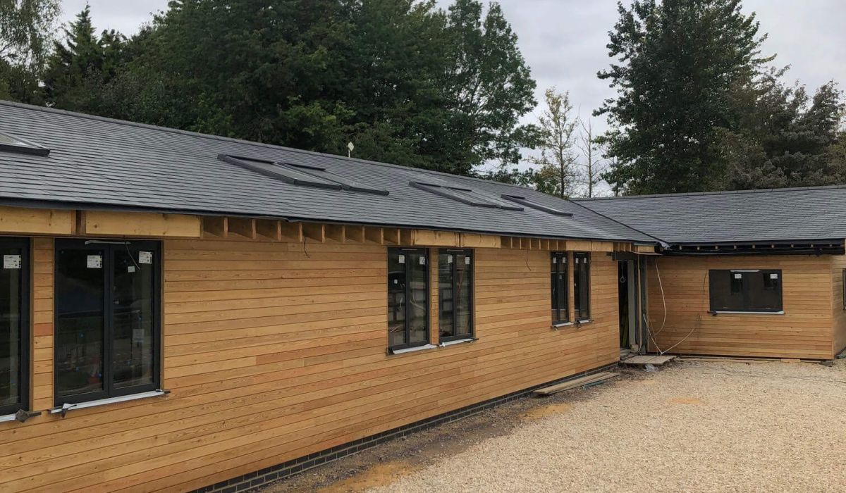A house roof featuring a prominent chimney at its peak against a clear blue sky.  