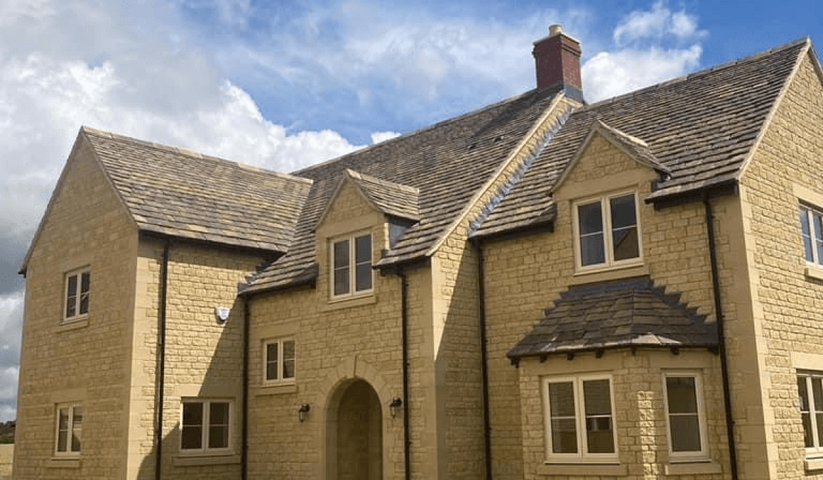 A stone building featuring a sloped roof and multiple windows, set against a clear sky.  