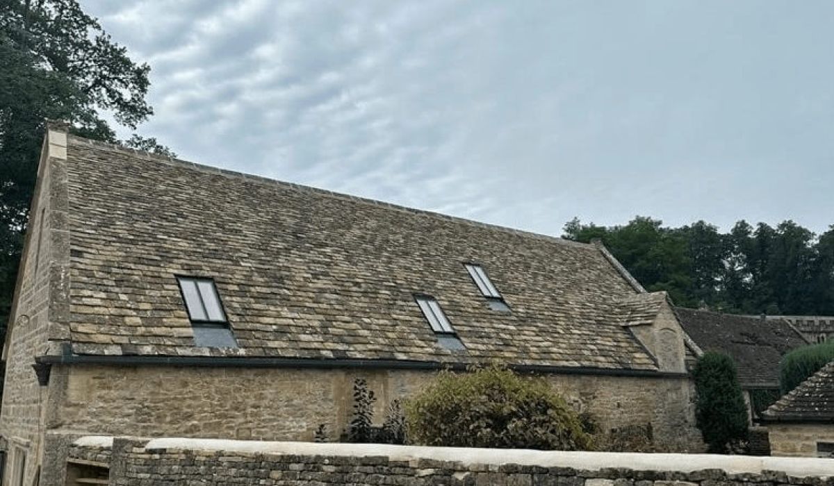 A stone building featuring a sloped roof and multiple windows, set against a clear sky.  