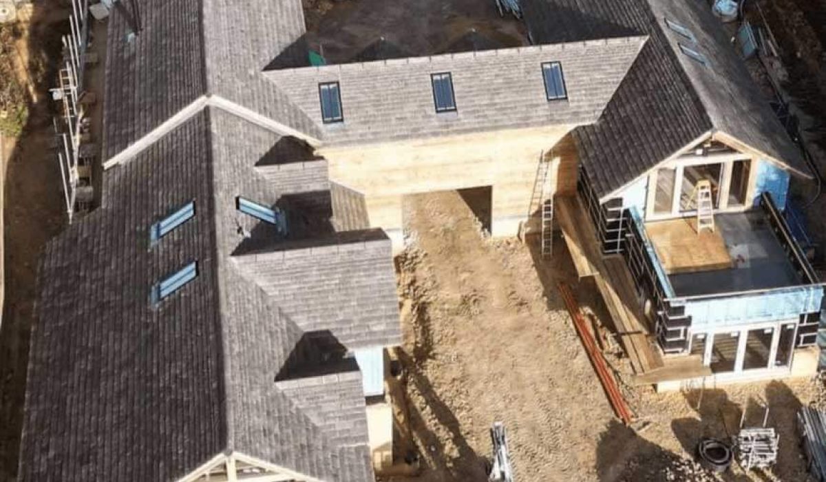 Aerial view of a house under construction, showcasing the framework and surrounding site preparations. 